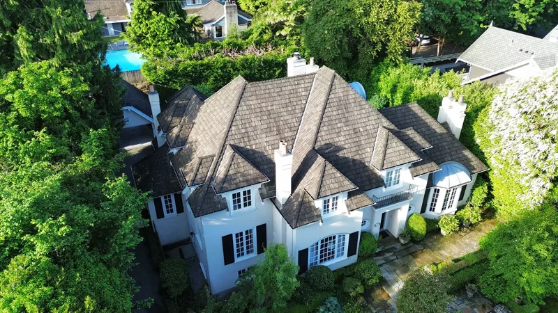 Aerial view of the aged cedar shake roof showing moss darkening and wear across the main hip